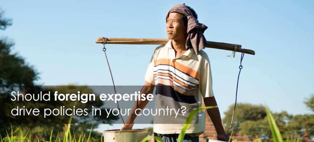 Asian farmer carrying water buckets with yoke asking should foreign expertise drive policies in your country