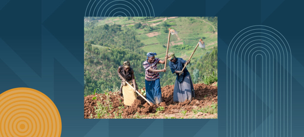 Three women farmers using traditional hoes to work soil in terraced hillside agricultural landscape