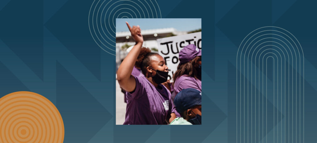 Woman in purple shirt raising fist at justice protest demonstration