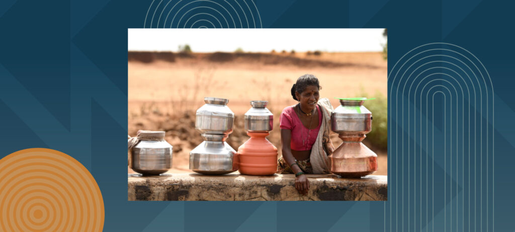 Woman sitting with metal water containers in rural setting during golden hour