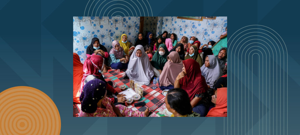 Group of women in colorful hijabs and traditional dress sitting together in community meeting room