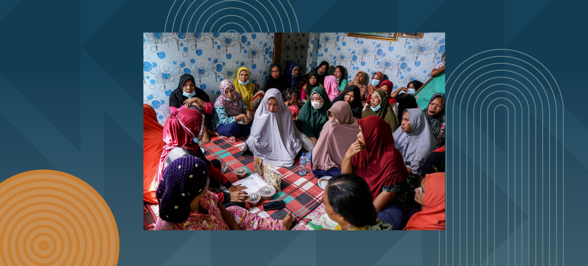 Group of women in colorful hijabs and traditional dress sitting together in community meeting room